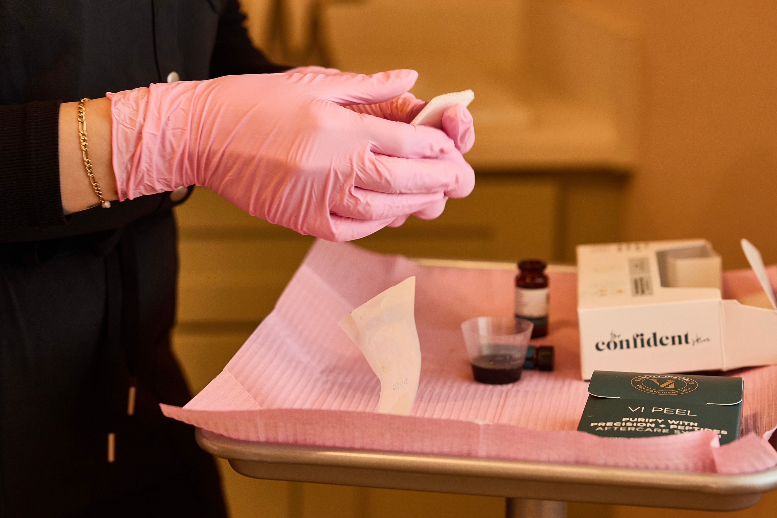 Gloved hands preparing skincare treatment materials.