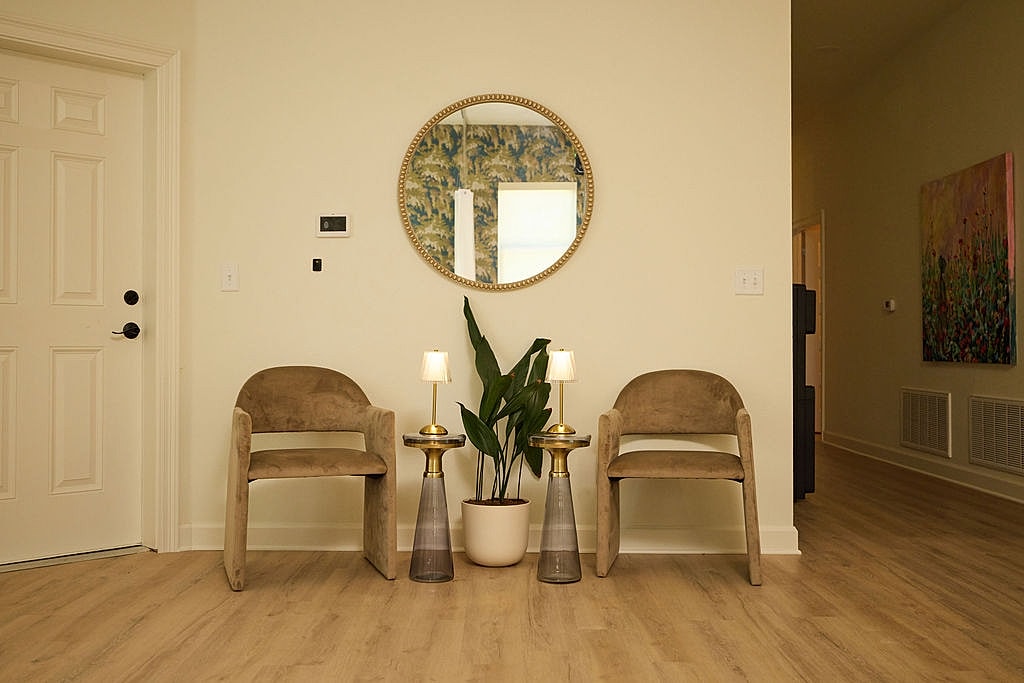 Modern entryway with chairs, plants, and mirror.