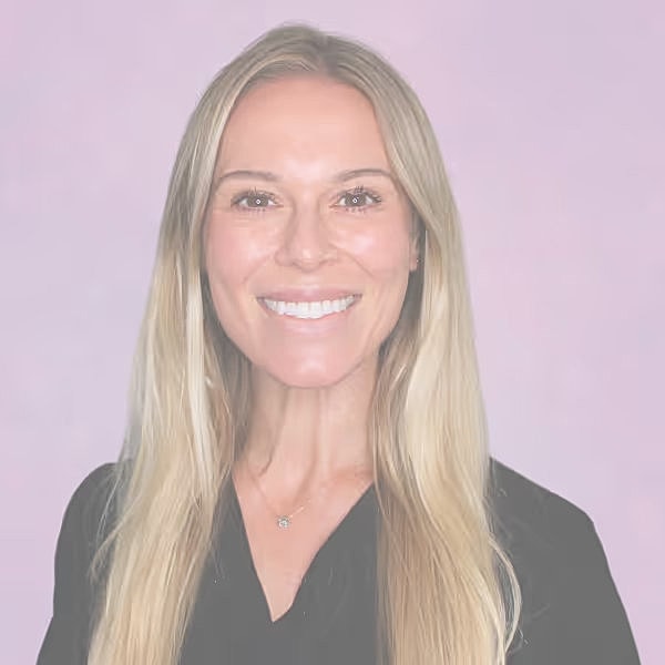 Smiling woman with long hair on pink background.