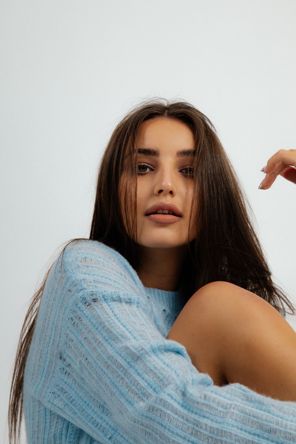 Woman in blue sweater, posing thoughtfully.