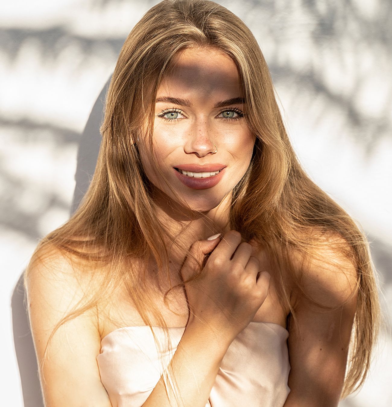 Woman smiling with sunlit hair and shadows.