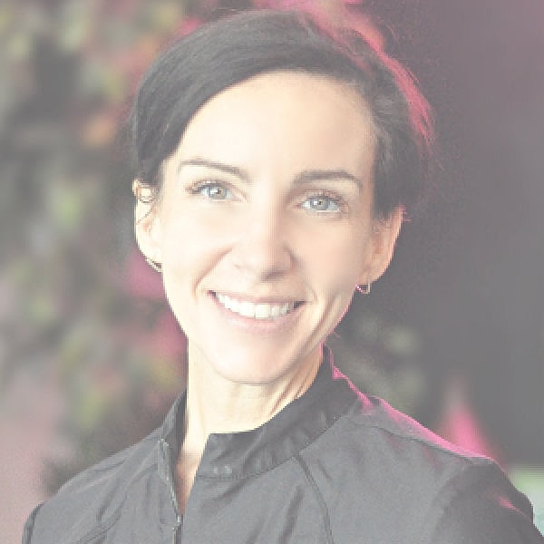 Professional woman smiling against gray background.