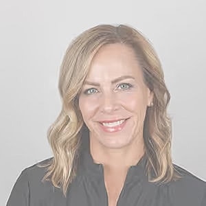 Professional woman smiling against gray background.