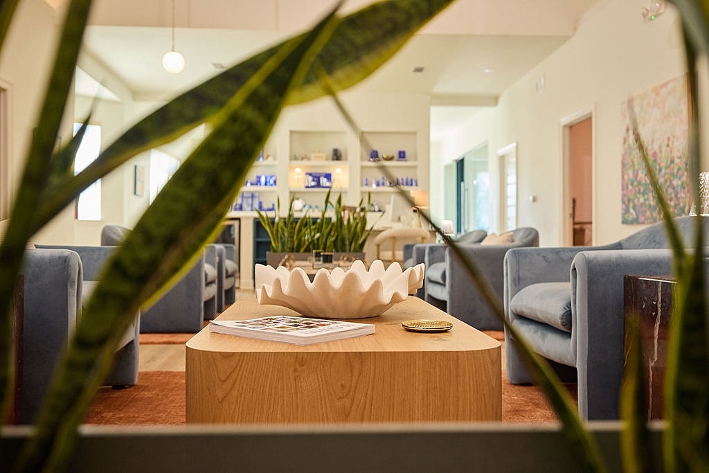 Model posing in studio, gray outfit, seated.