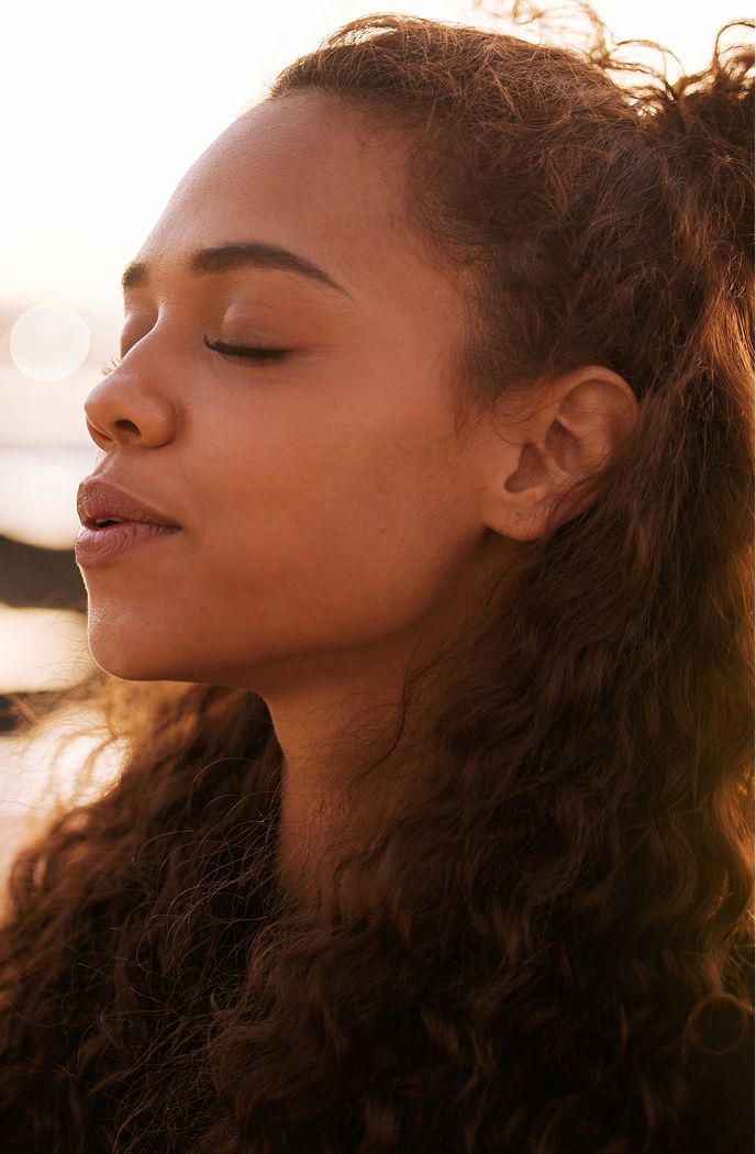 Woman with closed eyes enjoying sunset moment.