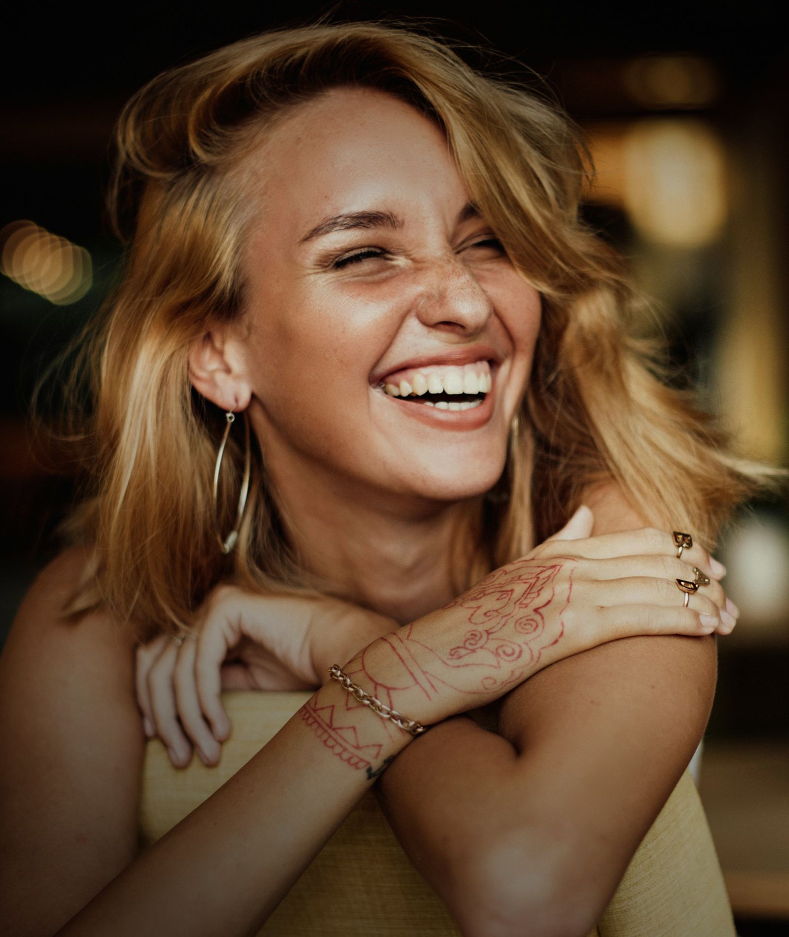 Smiling woman with patterned henna on her arm.
