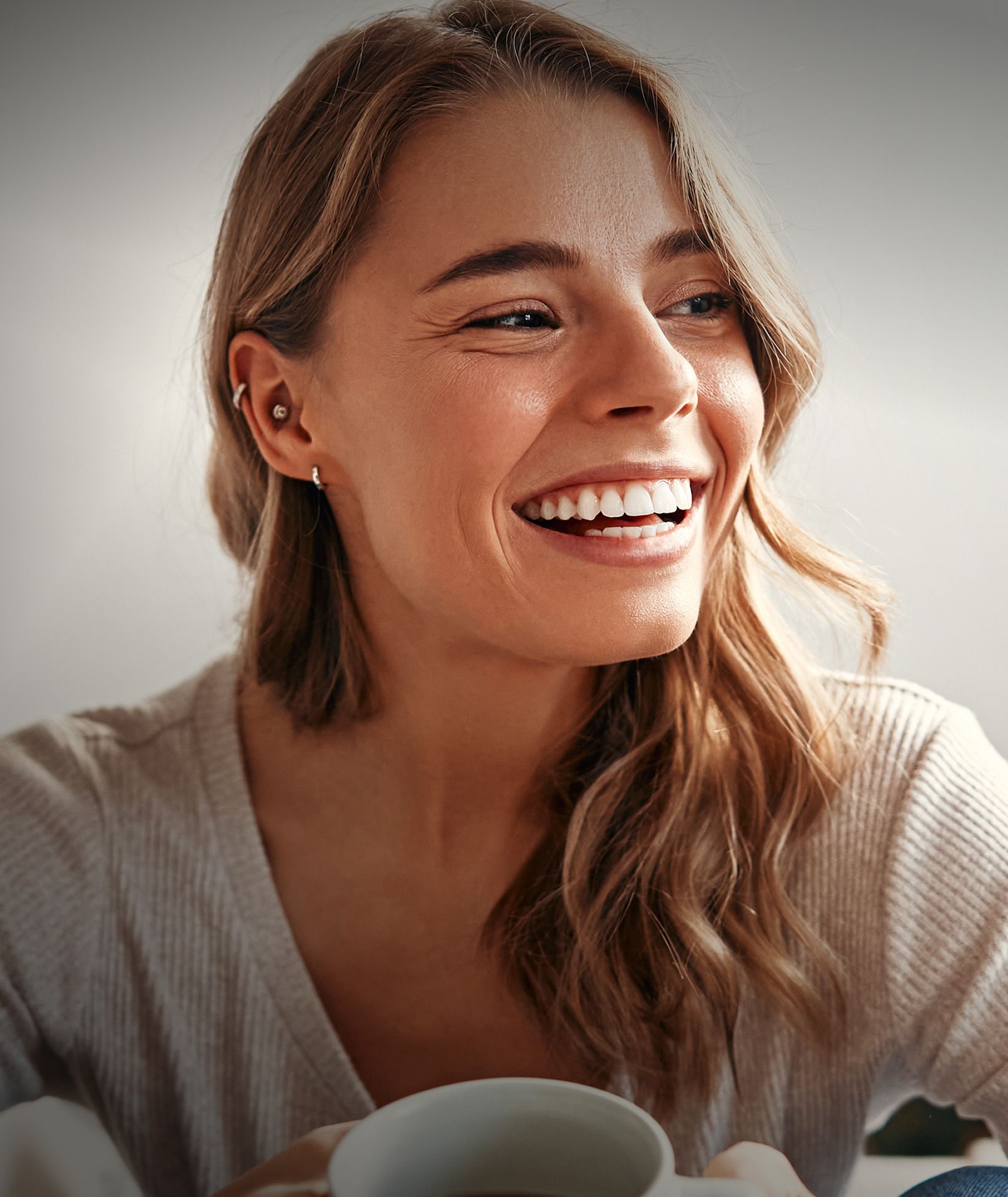 Woman with freckles smiling against neutral background.
