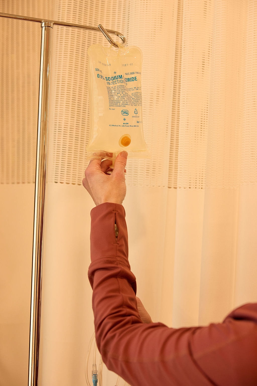 Person holding a saline IV bag in hospital.