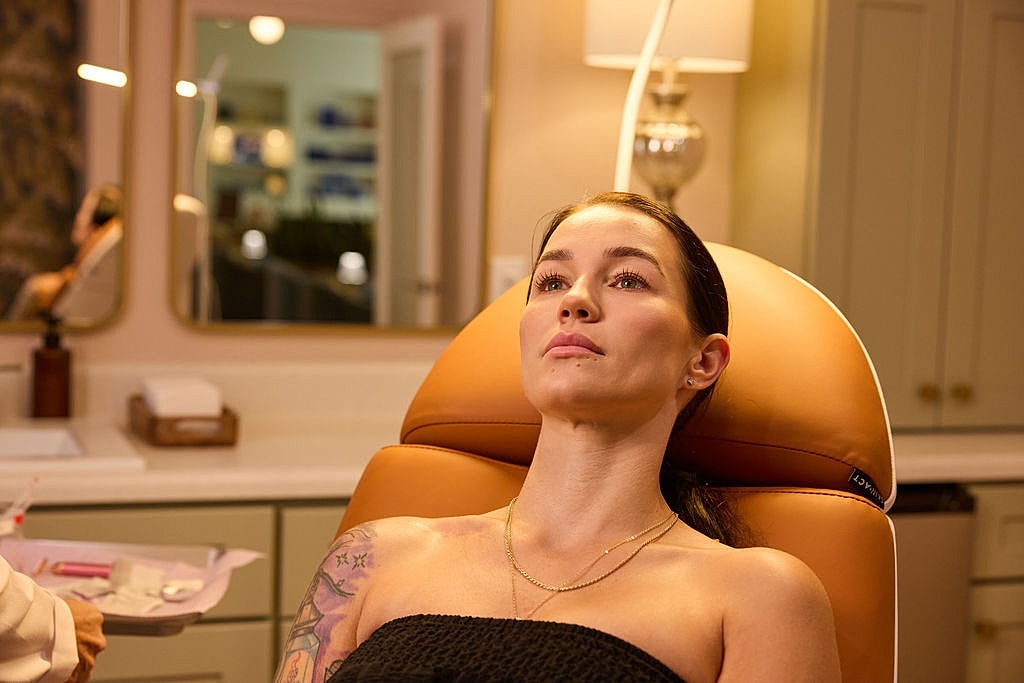 Woman applying skincare while looking in mirror